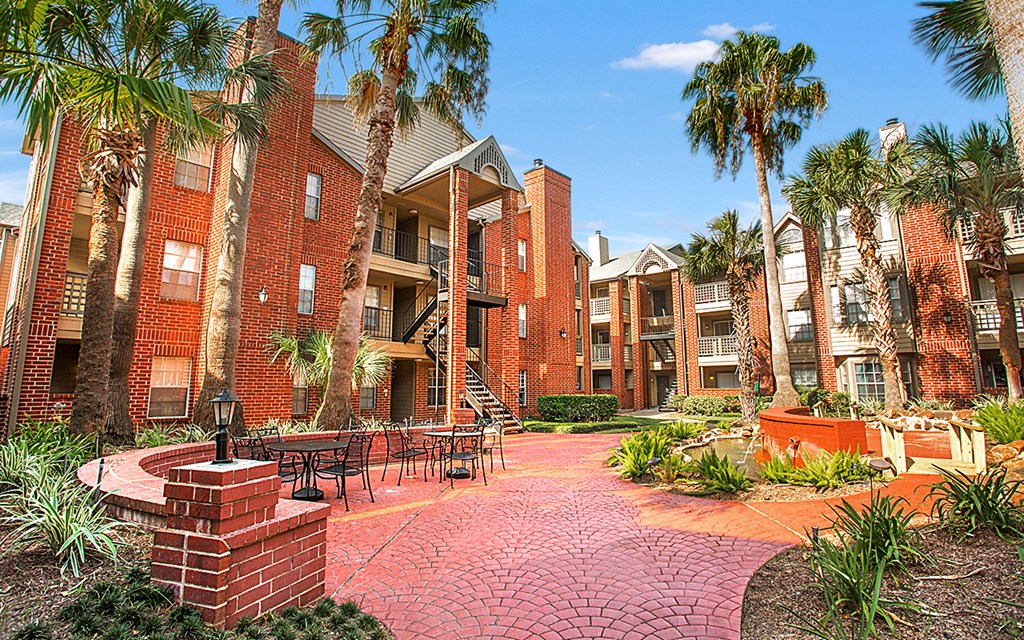an exterior view of apartments with a courtyard and palm trees