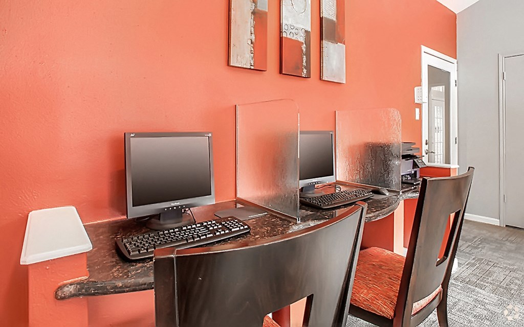 a computer desk with two monitors and chairs in a office