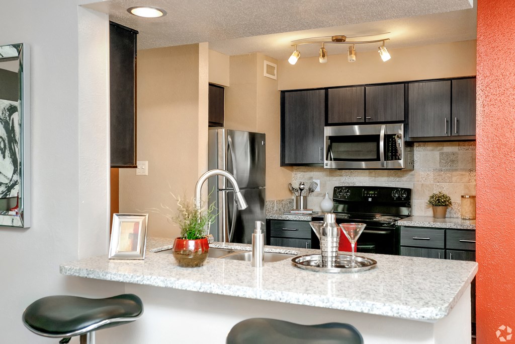 a kitchen with a granite counter top and a stainless steel refrigerator
