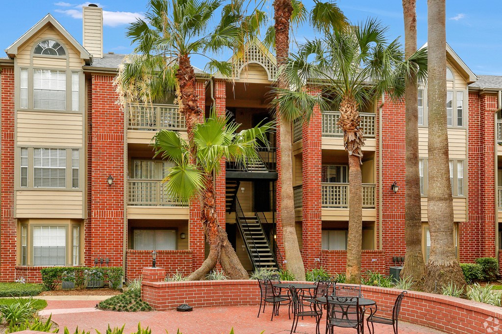 a courtyard with tables and chairs in front of an apartment building
