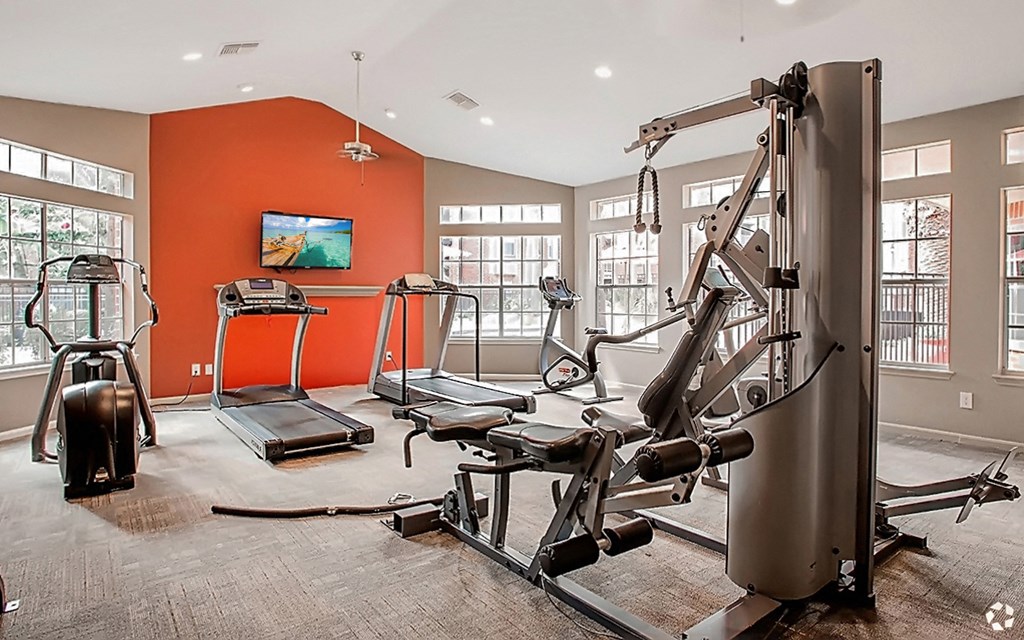 a gym with exercise equipment and a tv on the wall