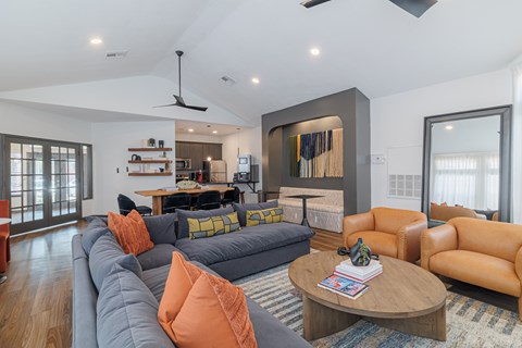 A living room with a grey couch and orange pillows.