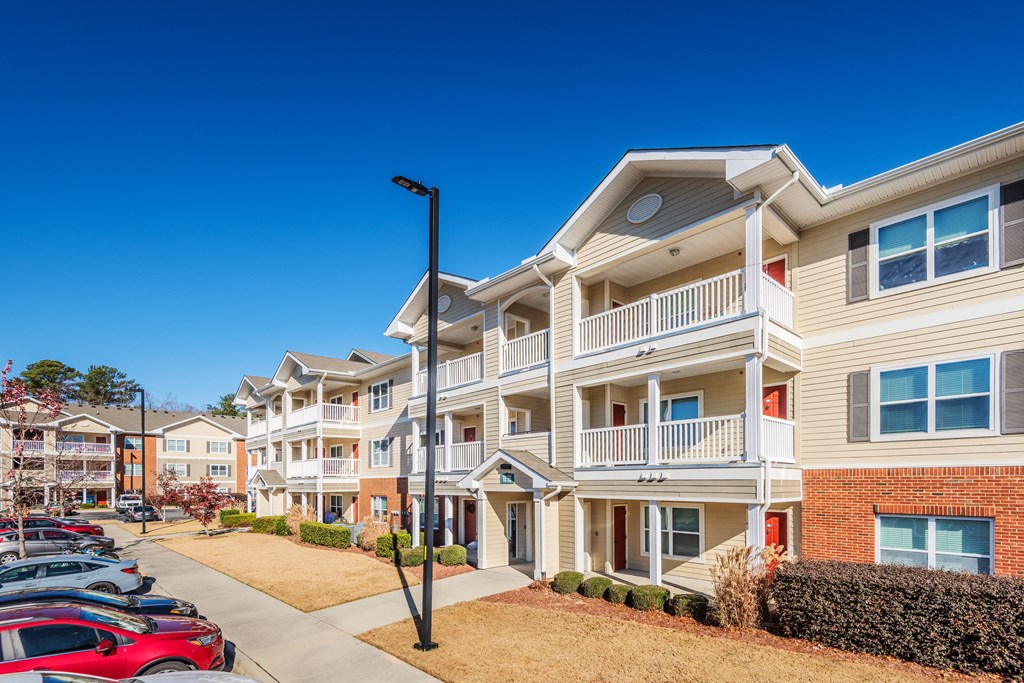 a row of apartment buildings with cars parked in front of them