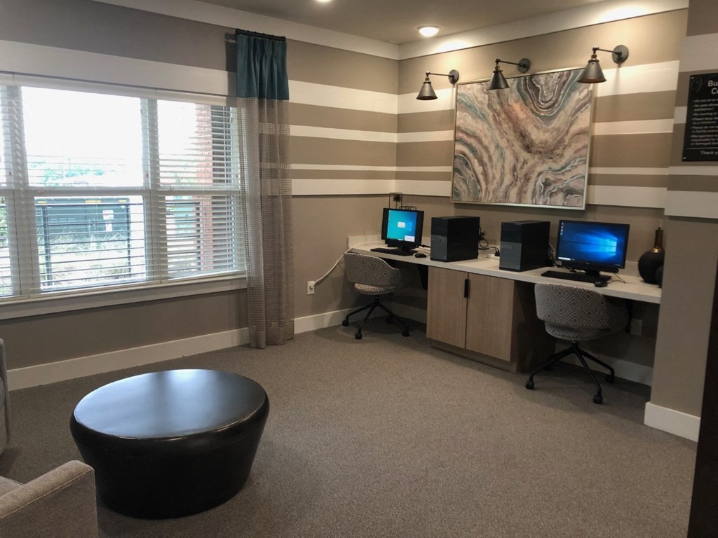 a home office with three computers and a painting on the wall