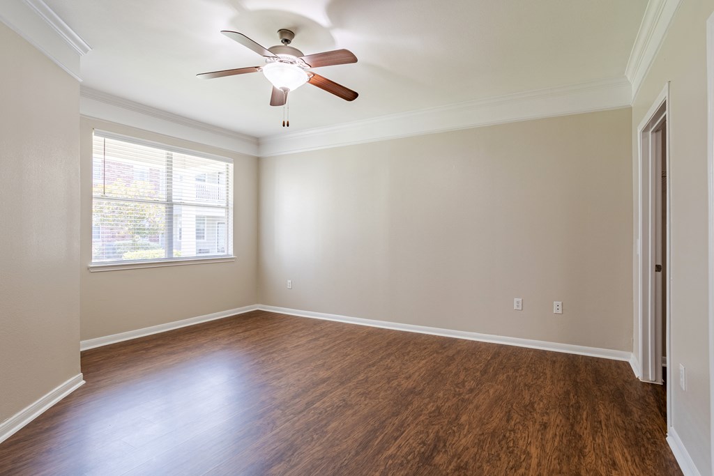 an empty living room with wood floors and a ceiling fan