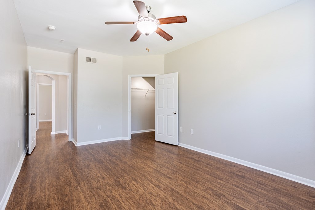 an empty living room with a ceiling fan and wood flooring