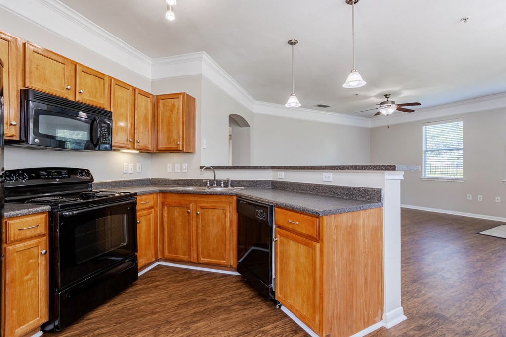 an empty kitchen with wooden cabinets and black appliances and a ceiling fan