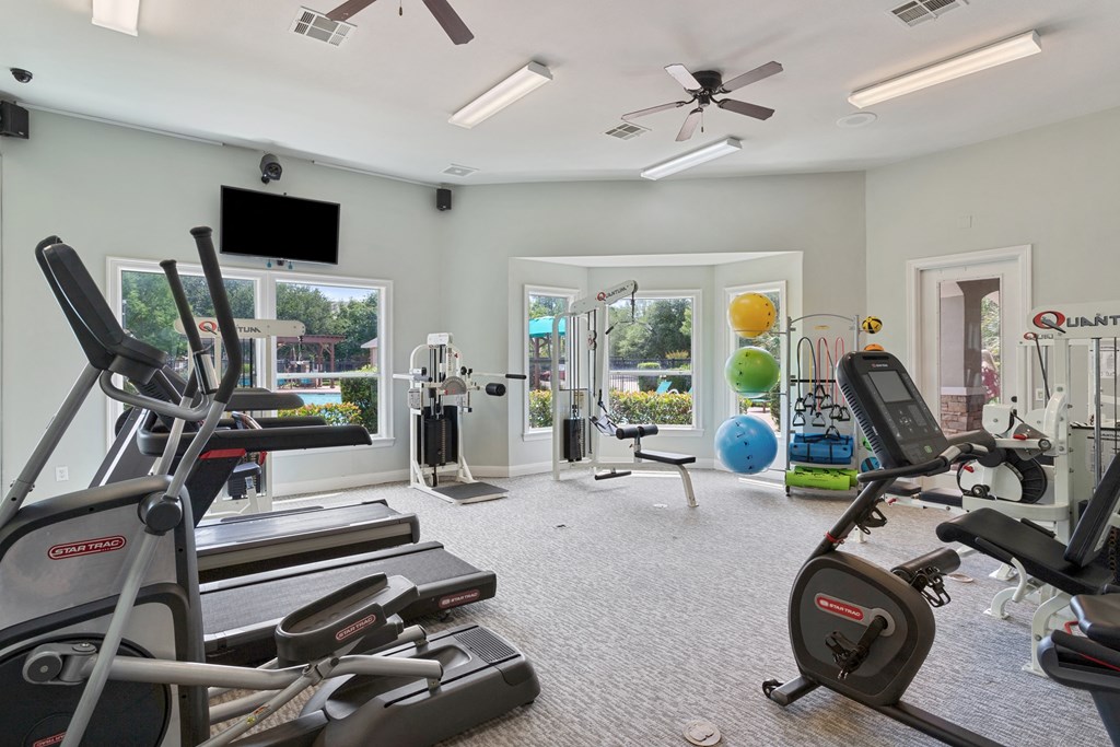 an exercise room with cardio equipment and a tv