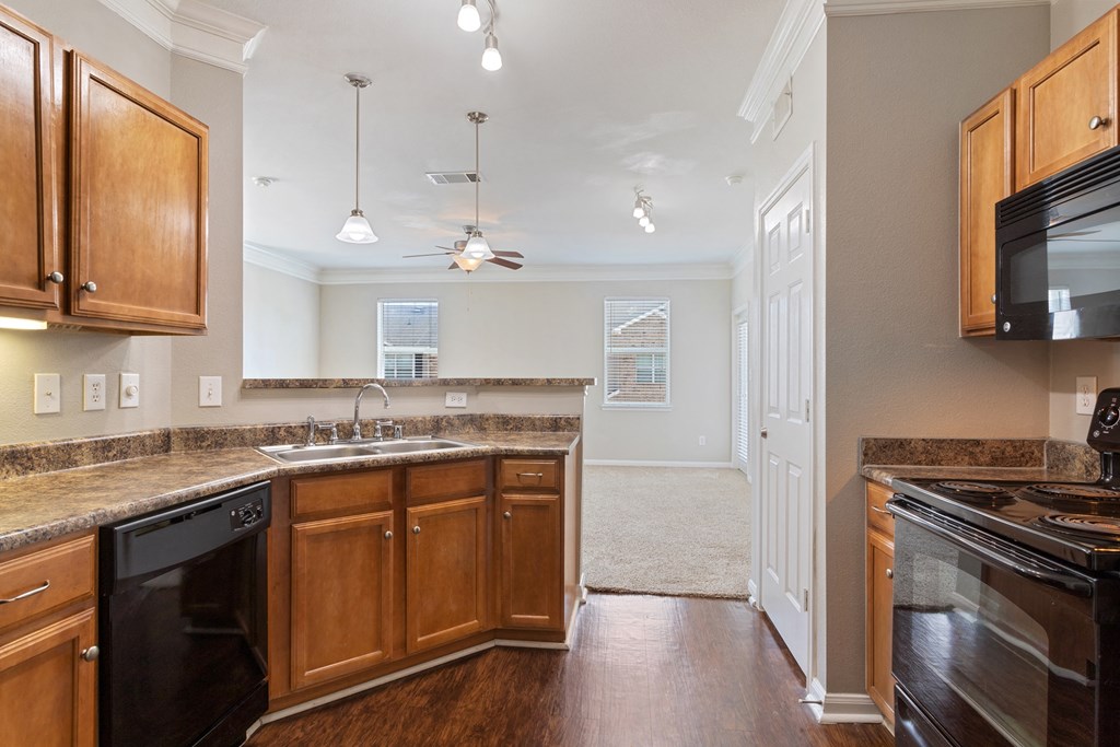 a kitchen with wooden cabinets, granite countertops, and black appliances