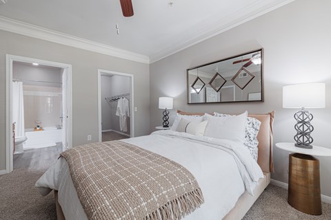 A bedroom with a large bed and a mirror on the wall.