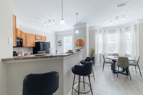 A kitchen with a bar area and a dining table with chairs.