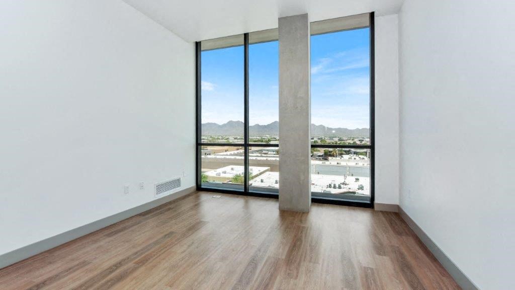 an empty living room with a large window and wood floors