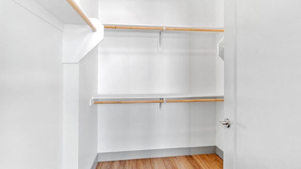 an empty closet with white walls and a wood floor