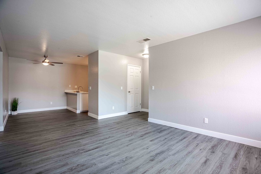 an empty living room with wood floors and a ceiling fan