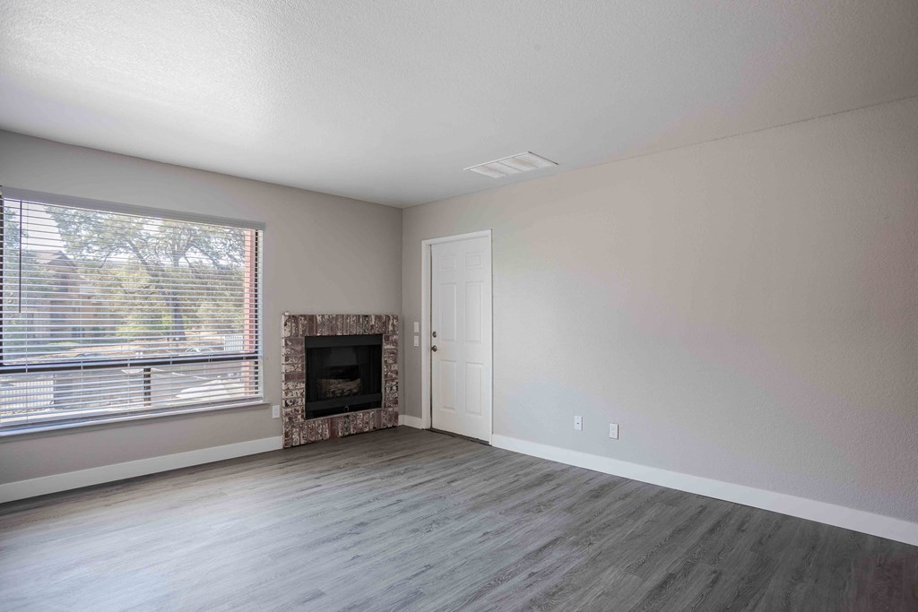 an empty living room with a fireplace and a window