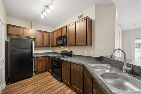 A kitchen with wooden cabinets and a black refrigerator.