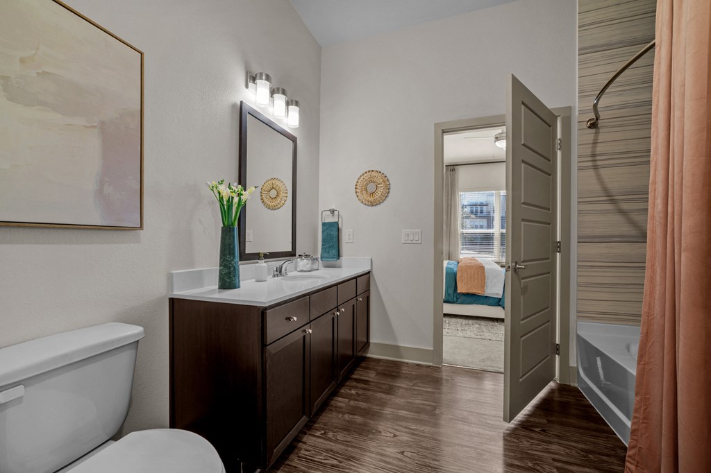 A bathroom with a white tub and a wooden vanity.