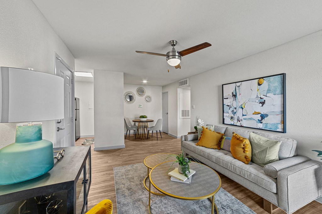 A living room with a grey couch, a yellow coffee table, and a painting on the wall.