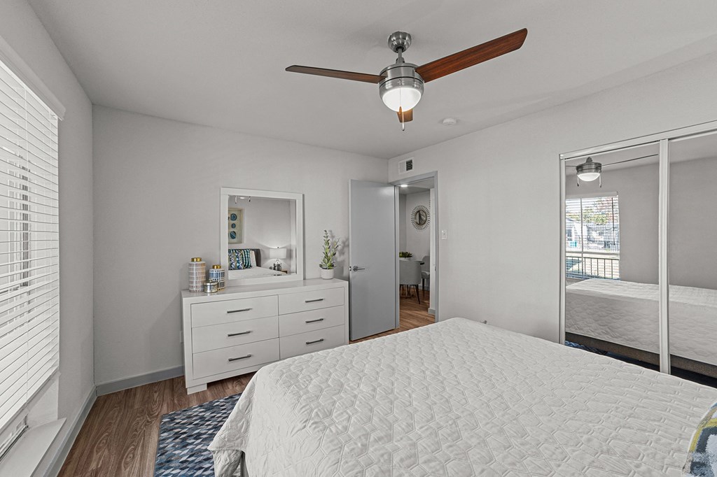 A white bedroom with a large bed and a ceiling fan.