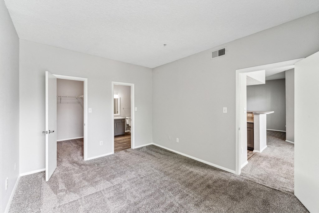 the living room of an apartment with carpet and a door to the bathroom