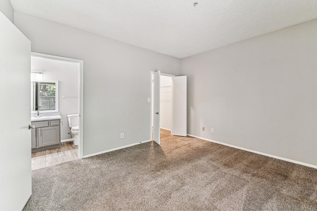 an empty living room with carpet and a bathroom
