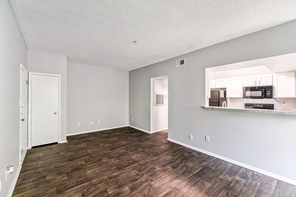 the living room and kitchen of an apartment with a hard wood floor