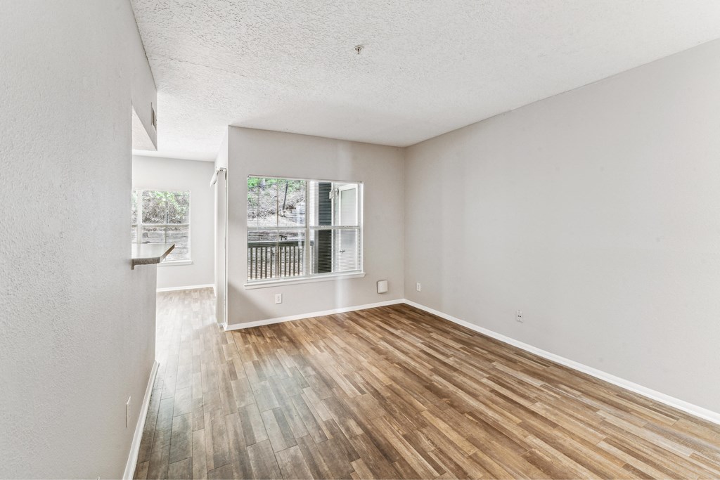 an empty living room with wood flooring and a window