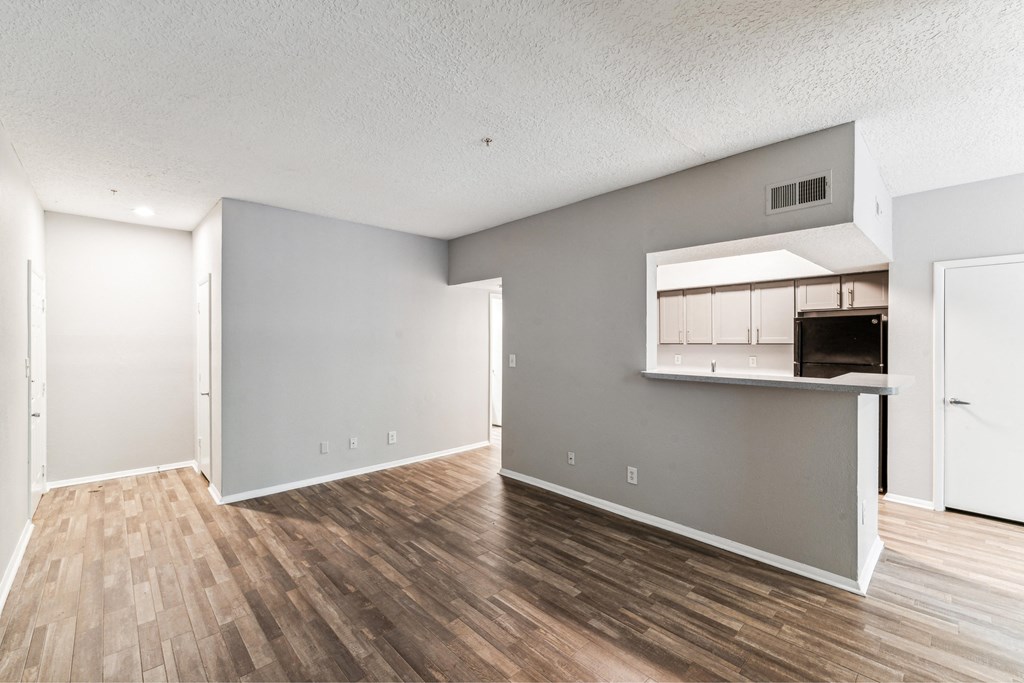 the living room and kitchen of an apartment with a hard wood floor
