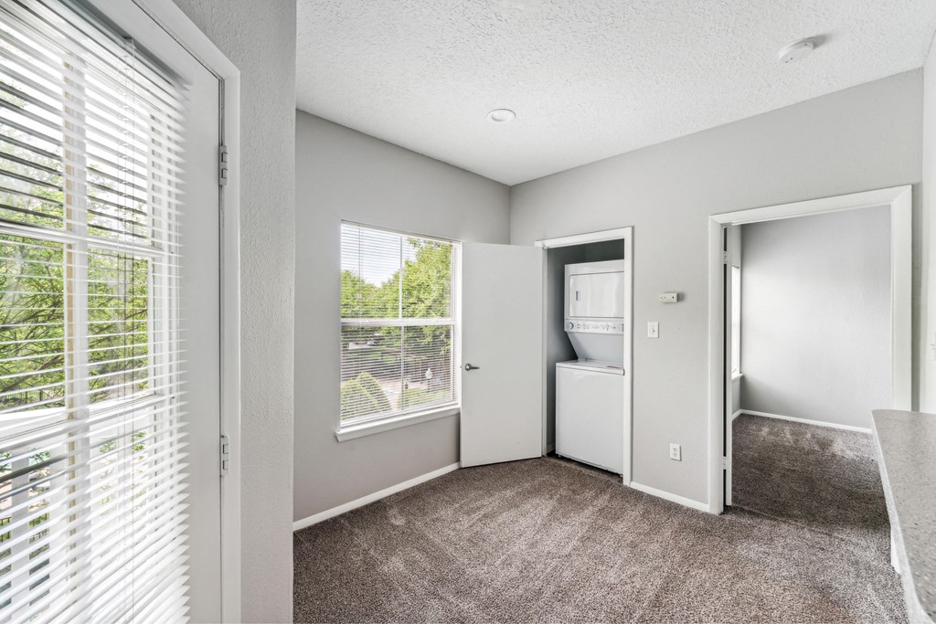 the living room of an apartment with a large window and a door to the bathroom