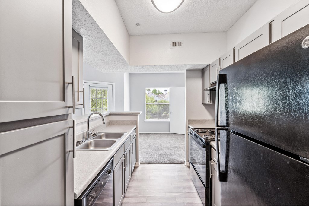an empty kitchen with stainless steel appliances and a black refrigerator