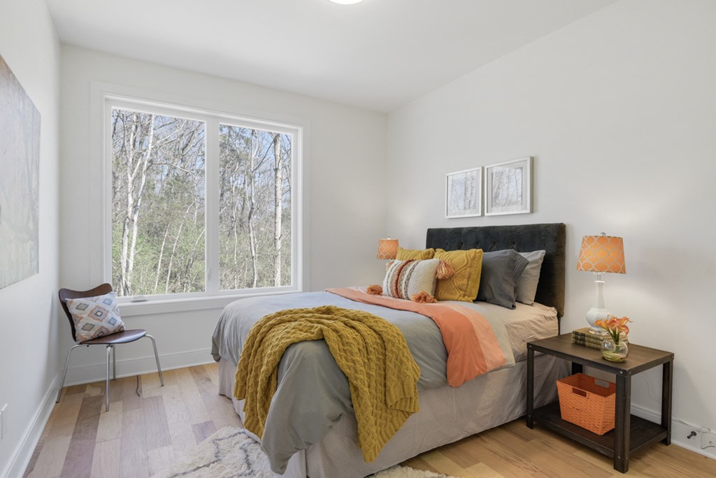 bedroom with a large window and a bed with a blanket and pillows