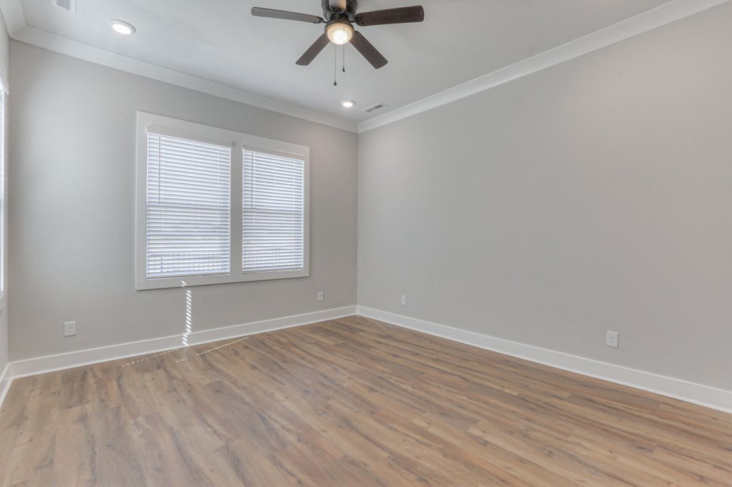 an empty living room with a ceiling fan and a window