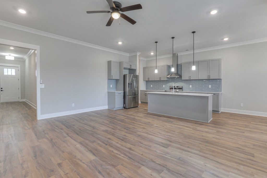 a living room with a kitchen and a ceiling fan