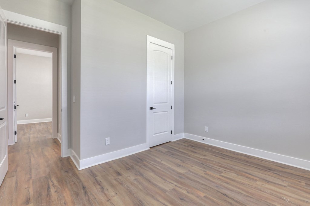 an empty living room with wood flooring and a white door