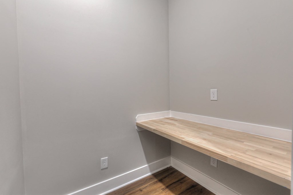 an empty room with a wooden shelf on the wall