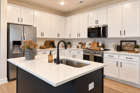 A kitchen with white cabinets and a black island.