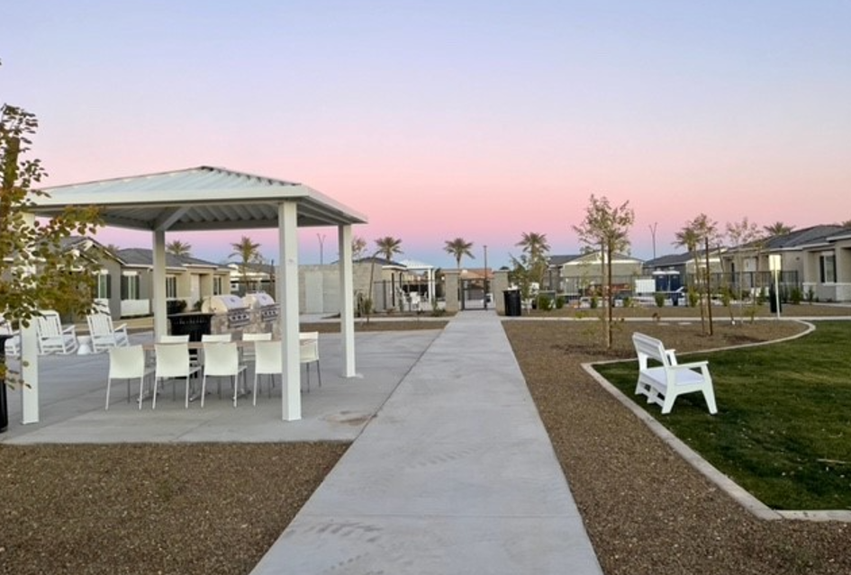 a pathway leading to a picnic area with chairs and tables