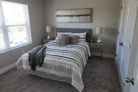 A bedroom with a bed, two lamps, and a painting on the wall.