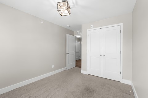 A room with a white door and a carpeted floor.