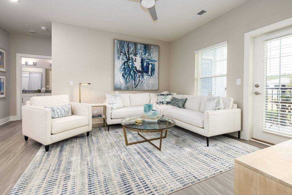 a living room with white couches and chairs and a rug