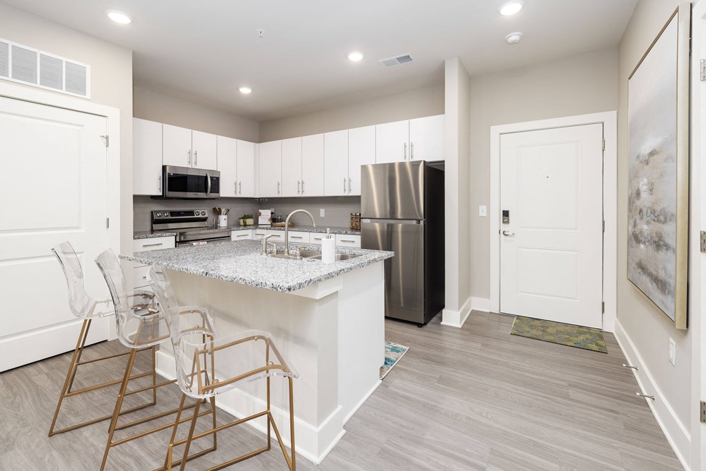a kitchen with white cabinets and a marble counter top and a stainless steel refrigerator