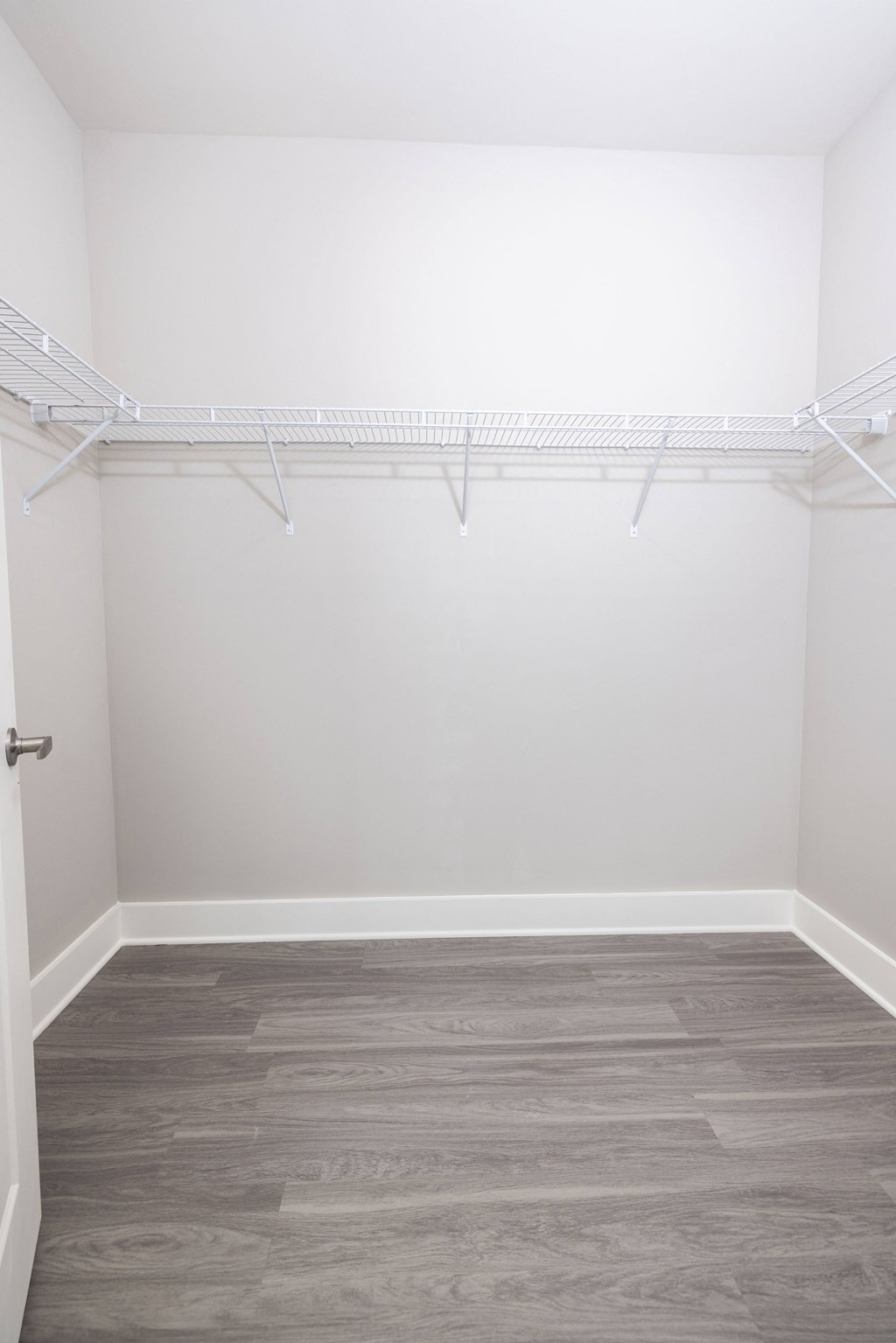 an empty closet with white walls and wood flooring