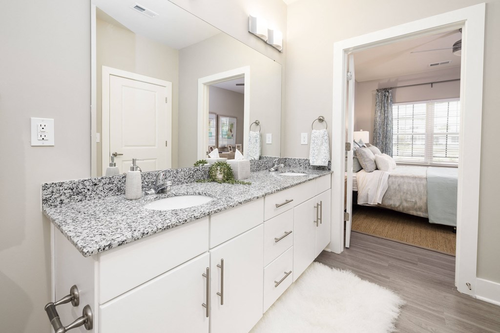 a white bathroom with granite counter tops and a large mirror