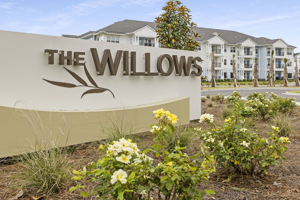 a sign for the willows with flowers in front of a building