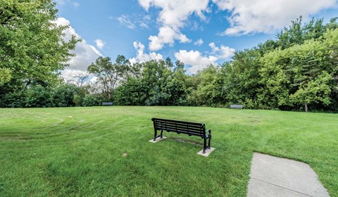 A park bench sits in the middle of a grassy field.