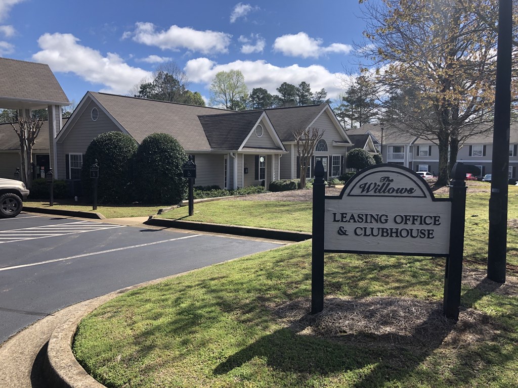 a building with a leasing office and clubhouse sign in front of it