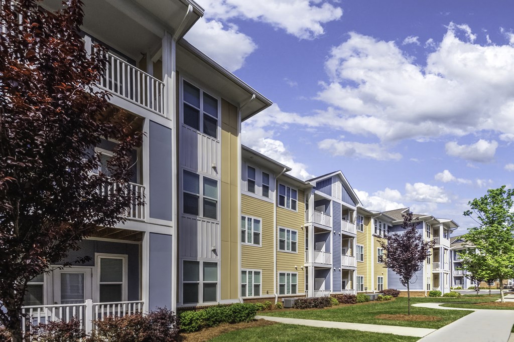 an exterior view of an apartment building with a sidewalk