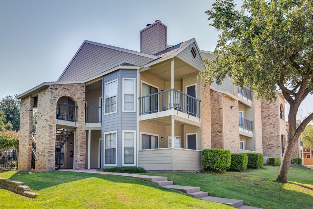 the outlook of an apartment building with a lawn and tree