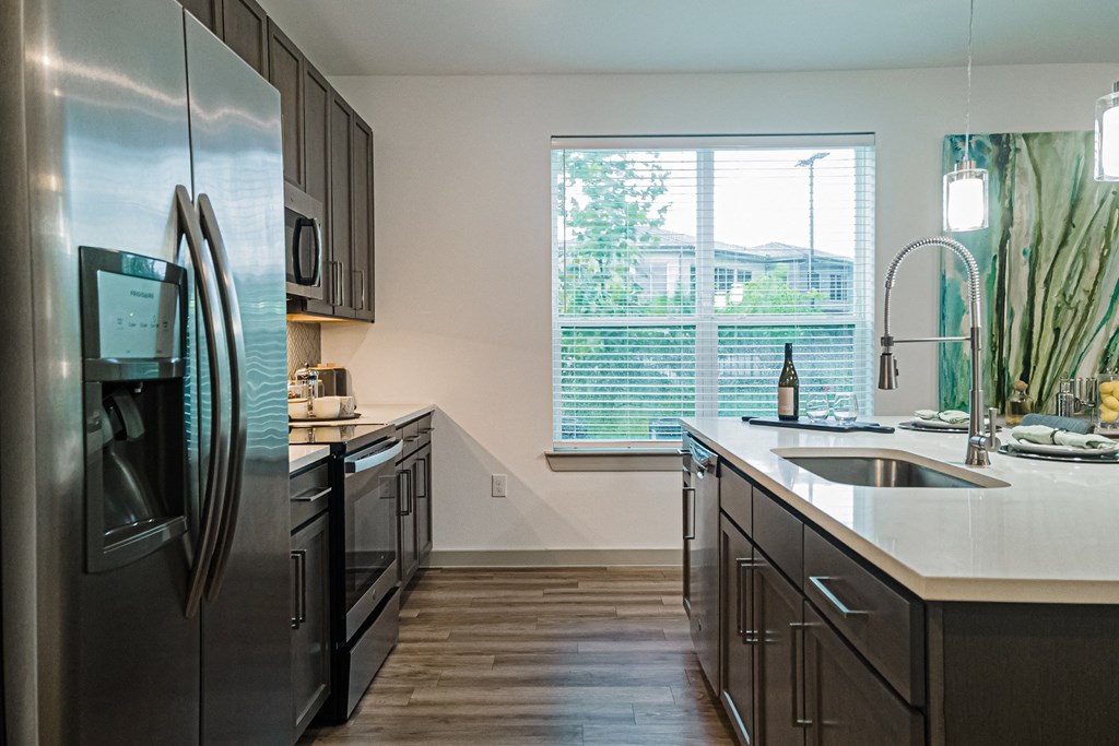 a kitchen with dark cabinets and a large window