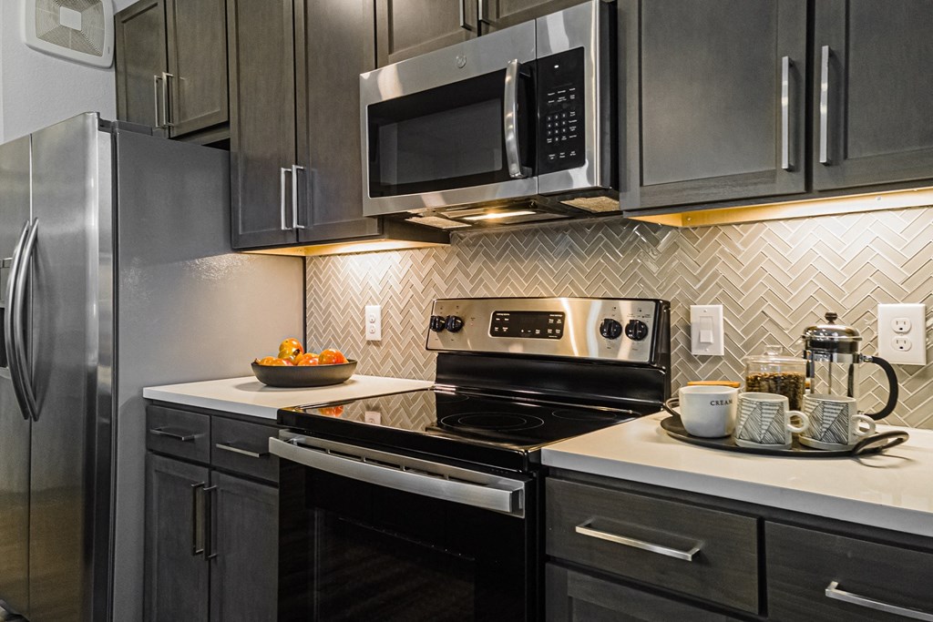 a kitchen with gray cabinets and white countertops